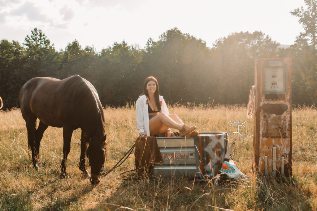 Gas pump cowgirl sitting on water trough with horse