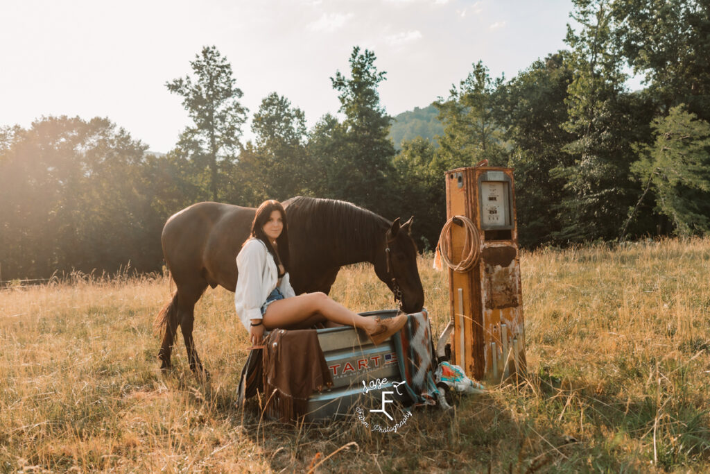 girl sitting on water trough with horse from the side