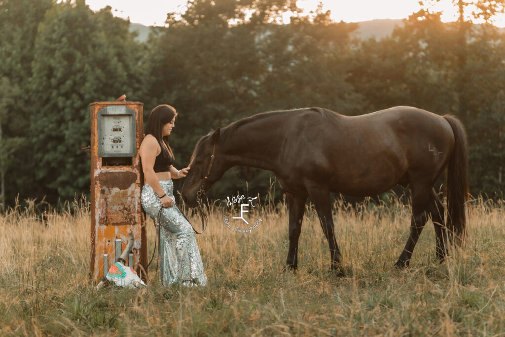 cowgirl in shiny pants with horse leaned against gas pump