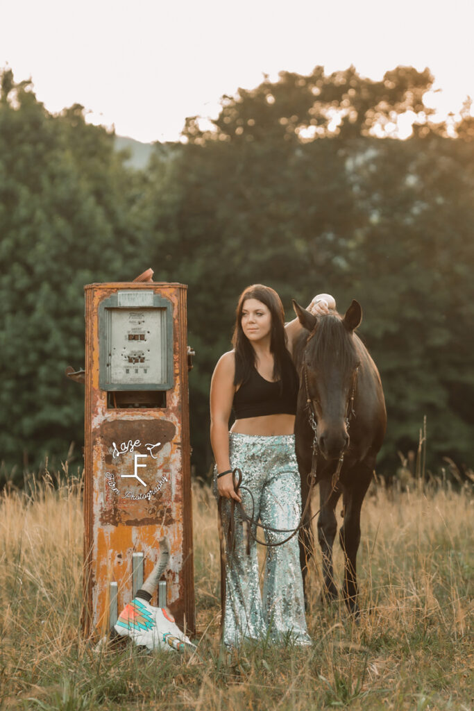 cowgirl in shiny pants with horse standing beside gas pump