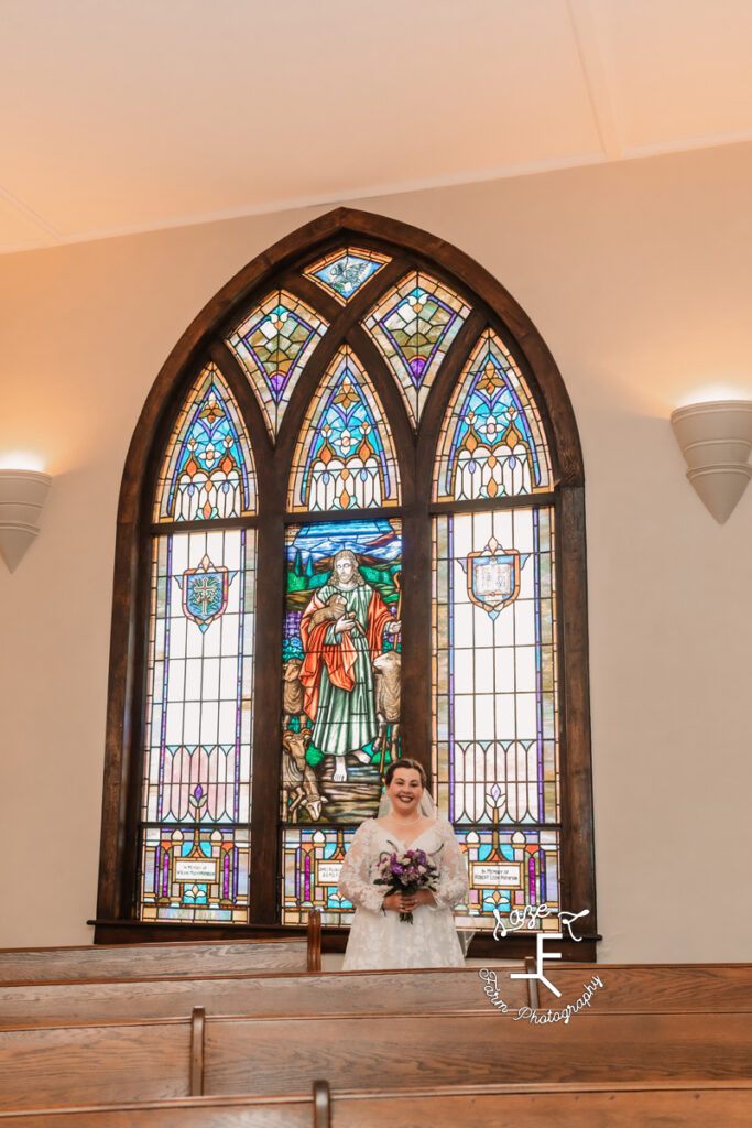 Bride in front of stained glass window at her home church