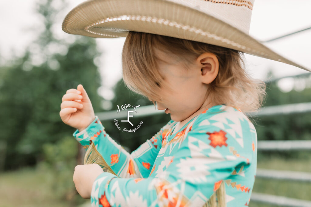 little cowgirl playing with fringe on shirt