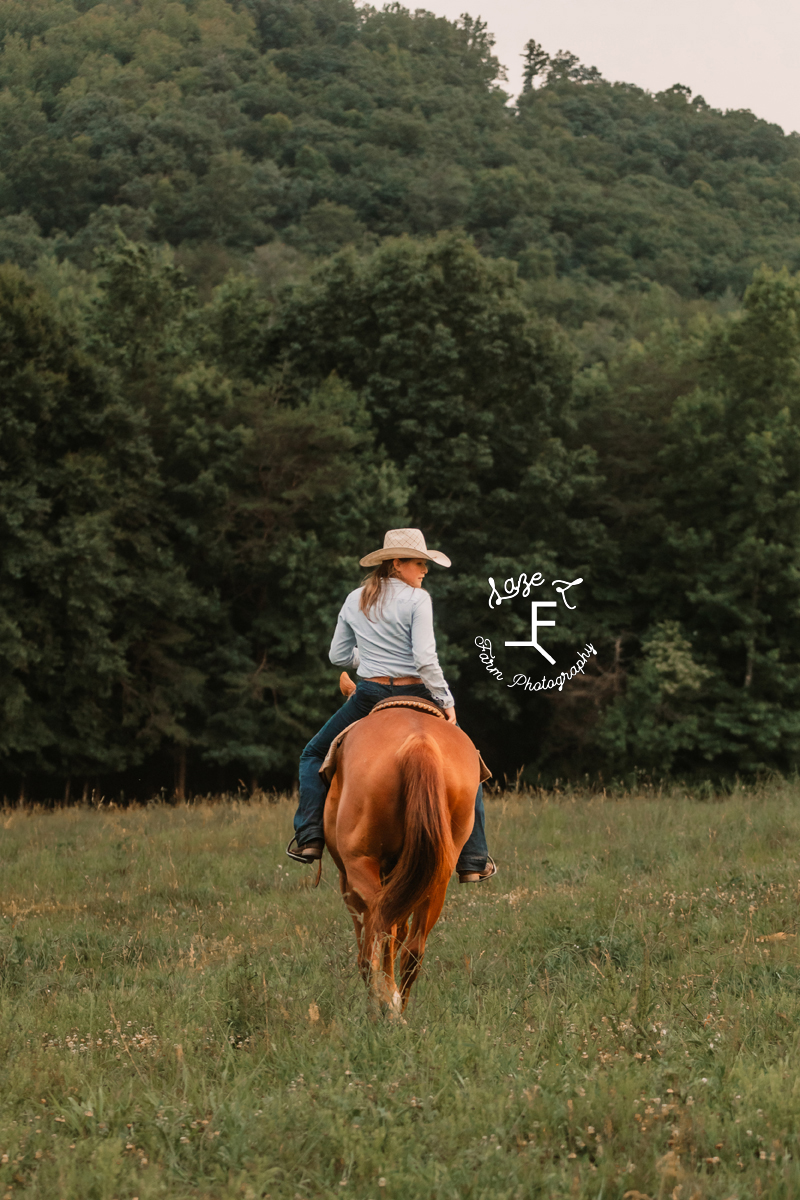 girl in black dress loping through field on horseback
