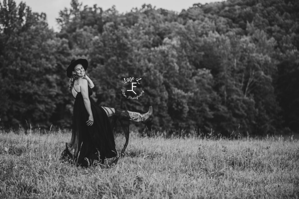 cowgirl in black dress kicking leg out in black and white