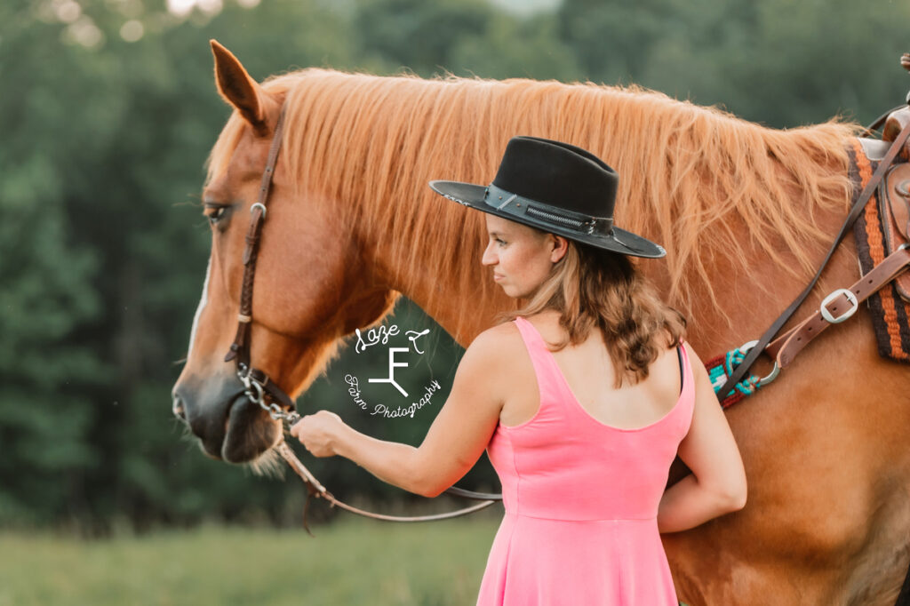 cowgirl in pink dress looking left with horse