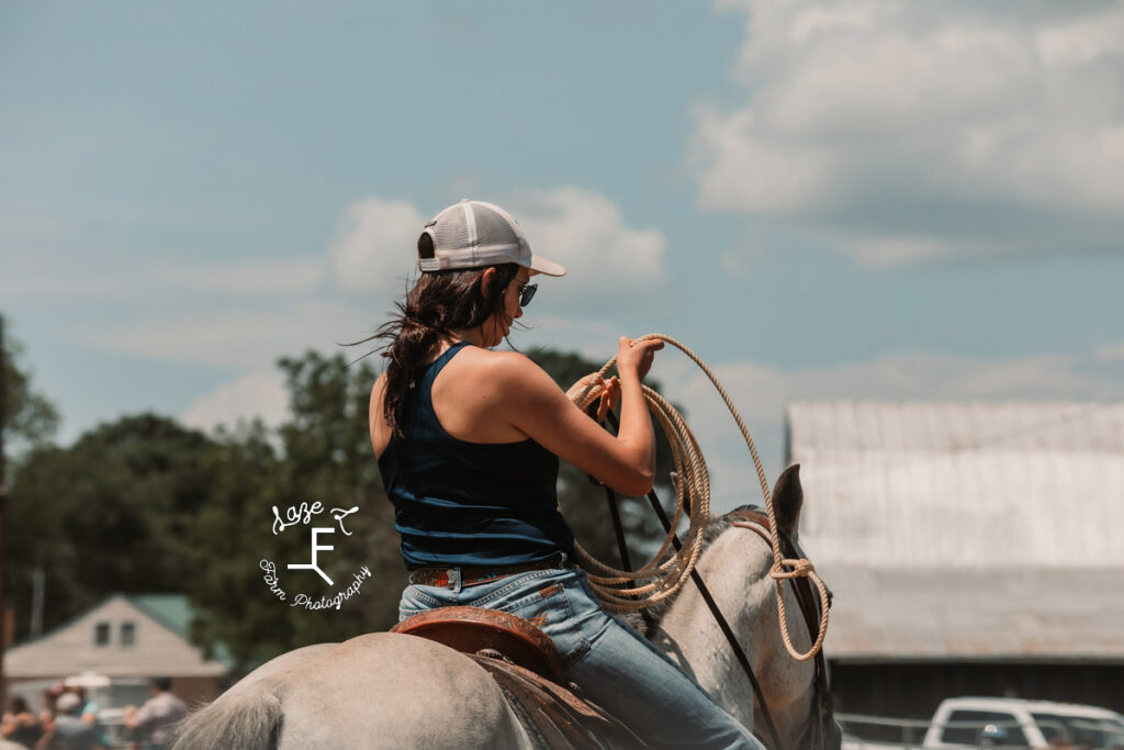 cowgirl on gray horse with rope from behind