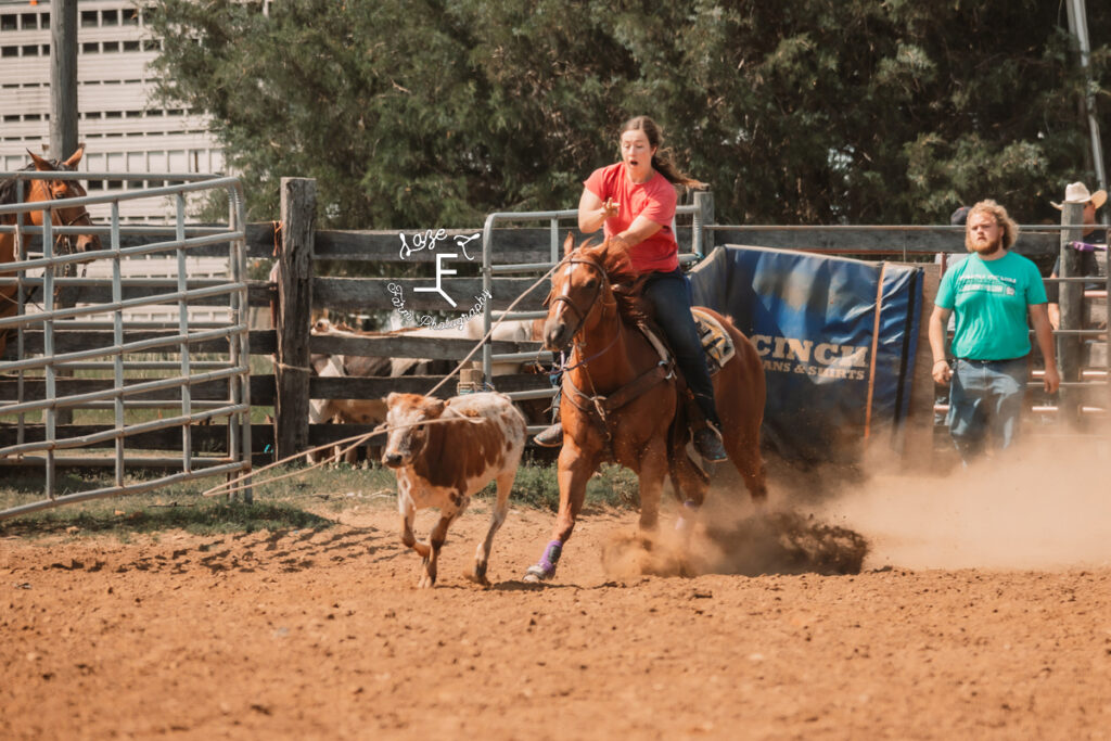 cowgirl in red shirt roping cow