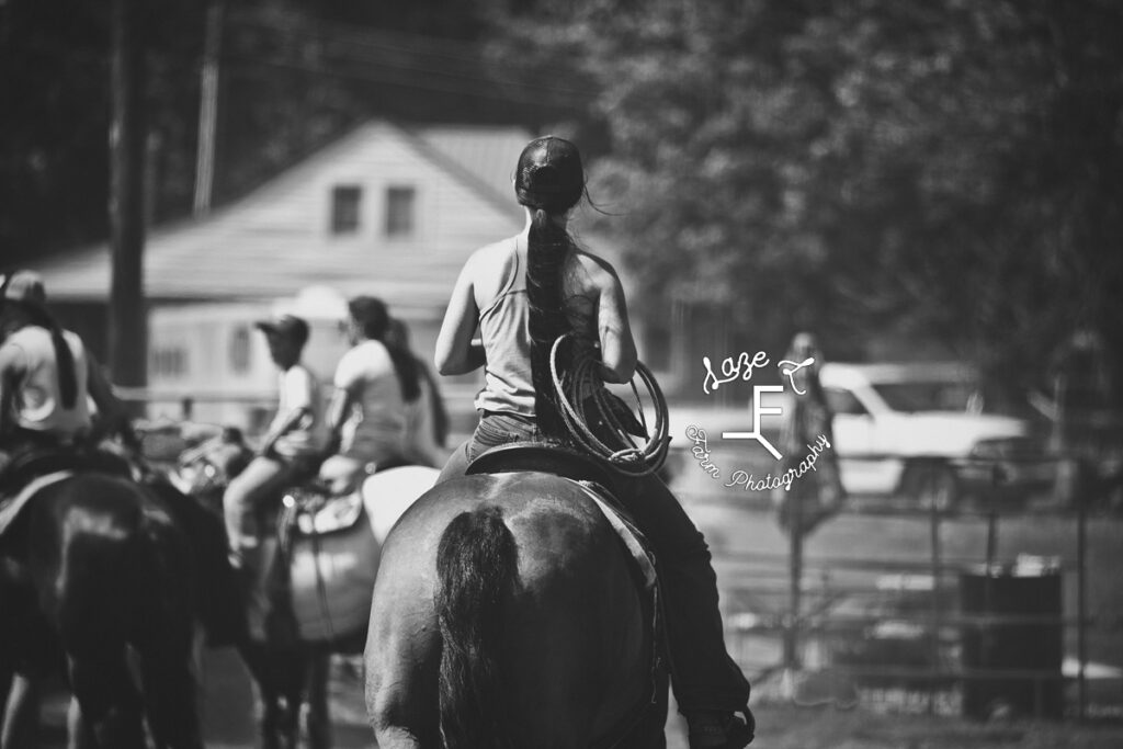 cowgirl with rope on horse in black and white
