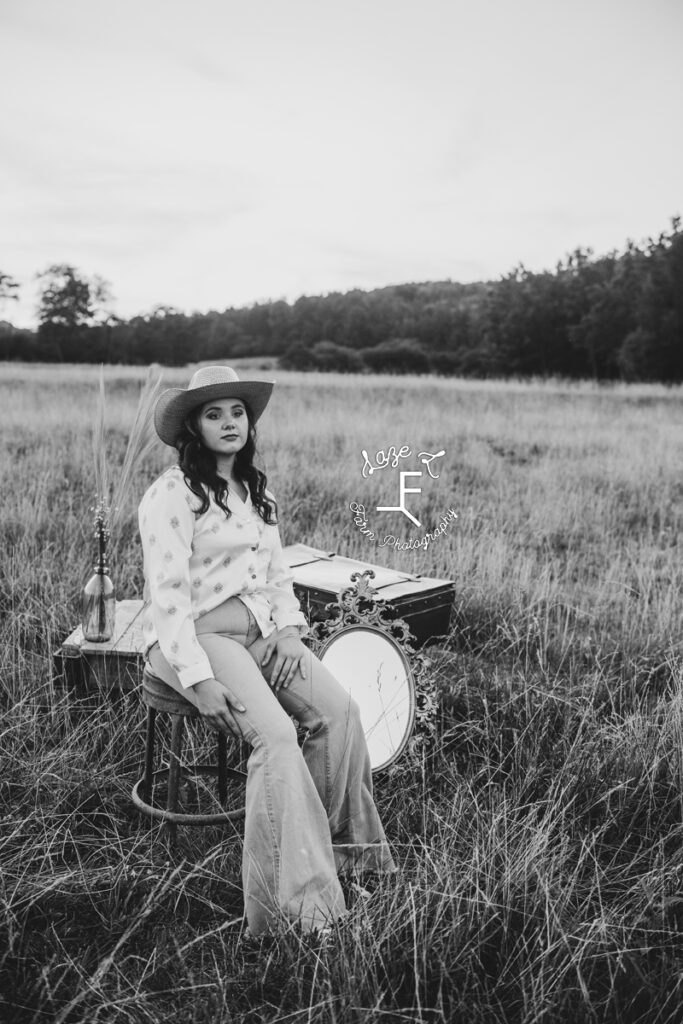 model sitting in field in button up and jeans in black and white