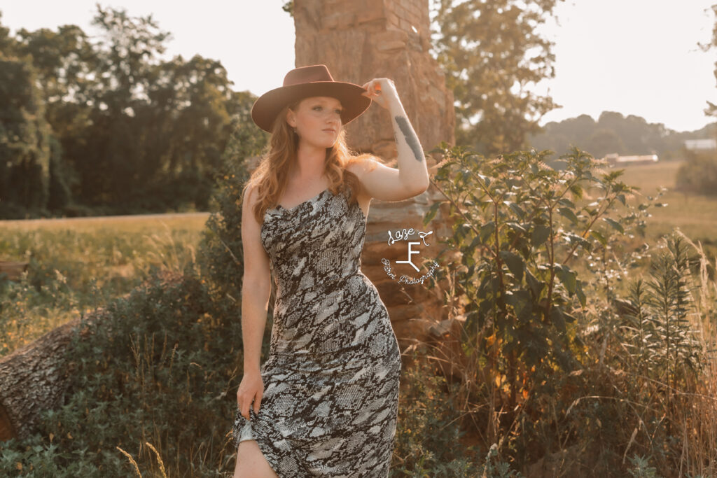 model standing holding hat in snake skin print dress