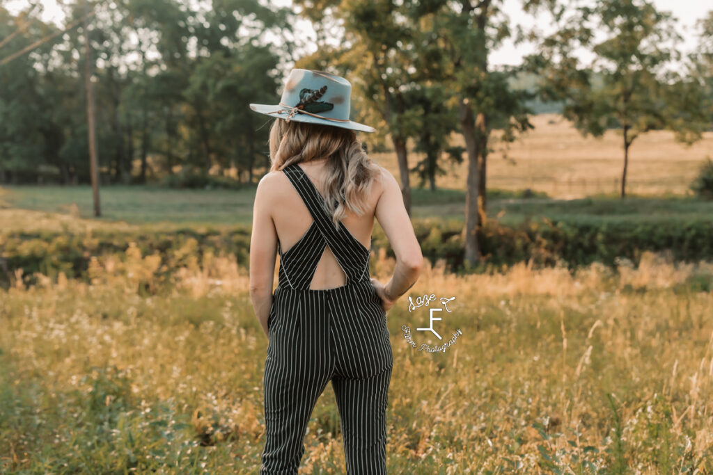 model wearing pinstripe black jumpsuit with blue hat from behind