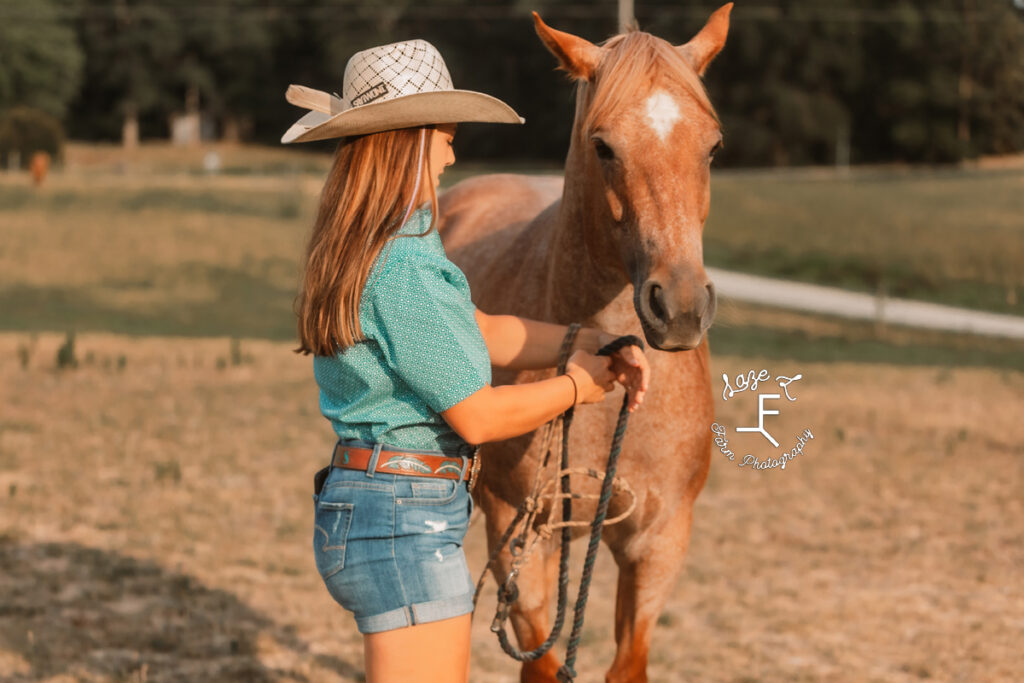 cowgirl in jean shorts haltering her horse