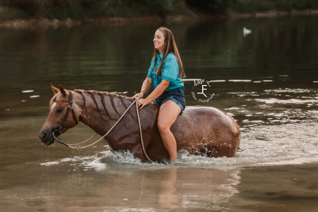 cowgirl swimming with red roan in pond