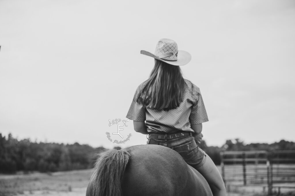 cowgirl riding bareback away from camera in black and white
