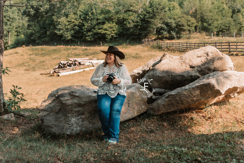 cowgirl photographer sitting on rock looking left