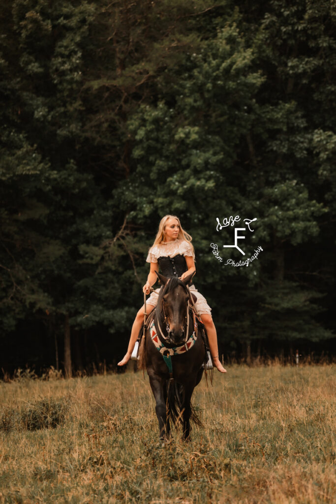 blonde girl in vintage dress riding black horse