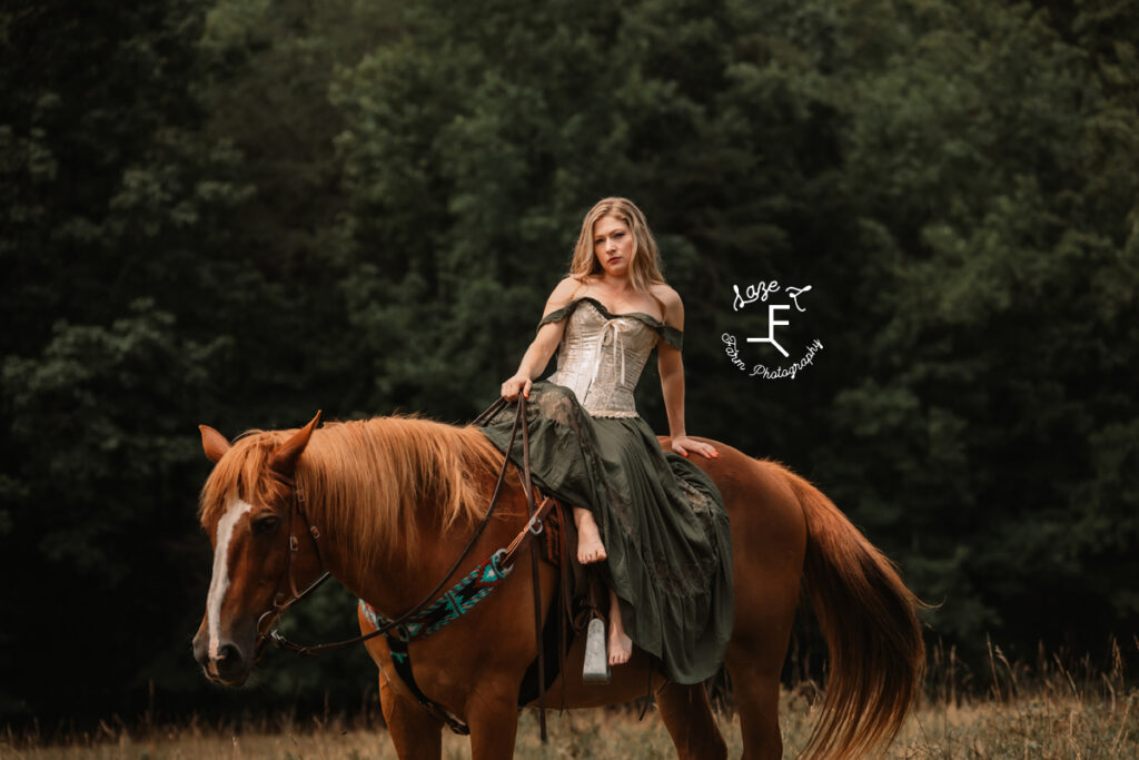 model in green dress sitting side saddle on brown horse