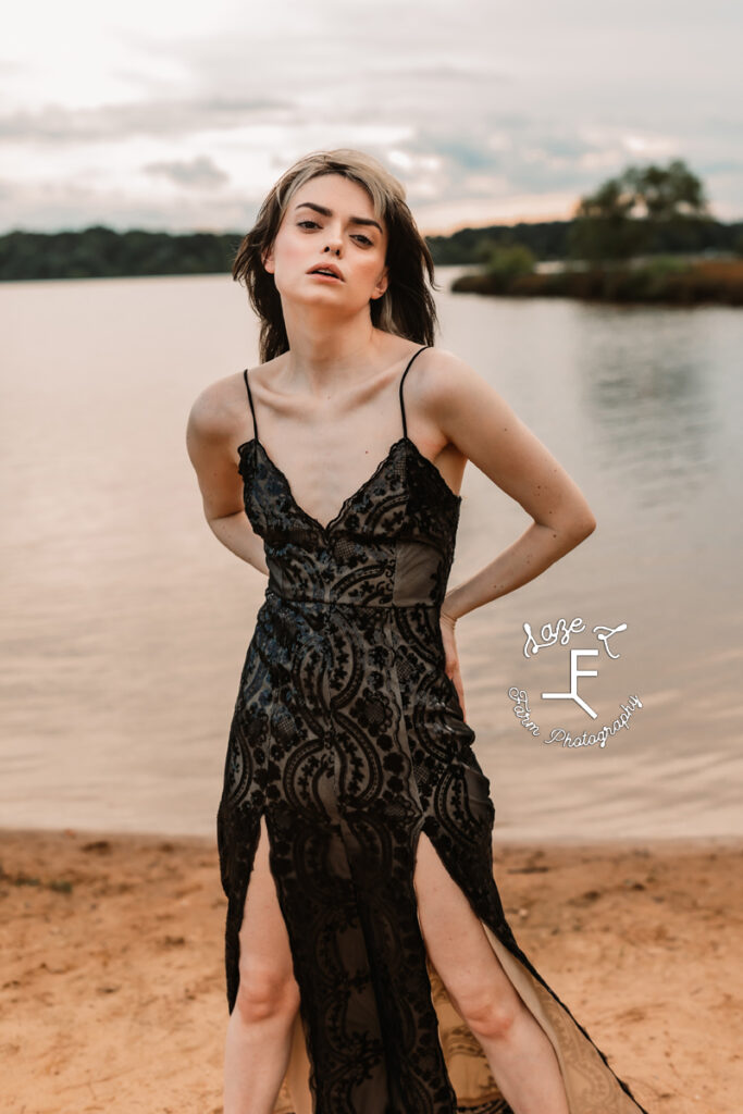 model in black lace dress standing at lake