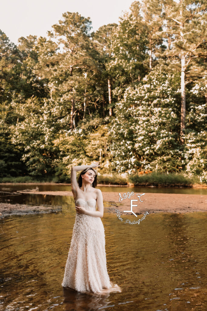 model in white dress standing in creek