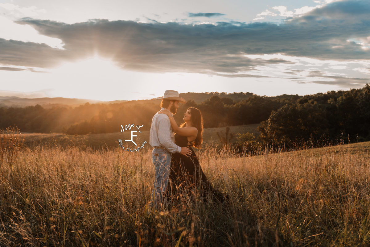 cowboy and fiancé at sunset in a field of brown grass