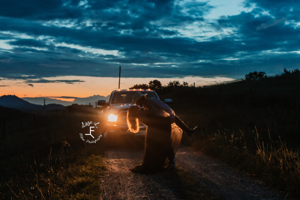 couple at sunset dipping in the truck headlights light
