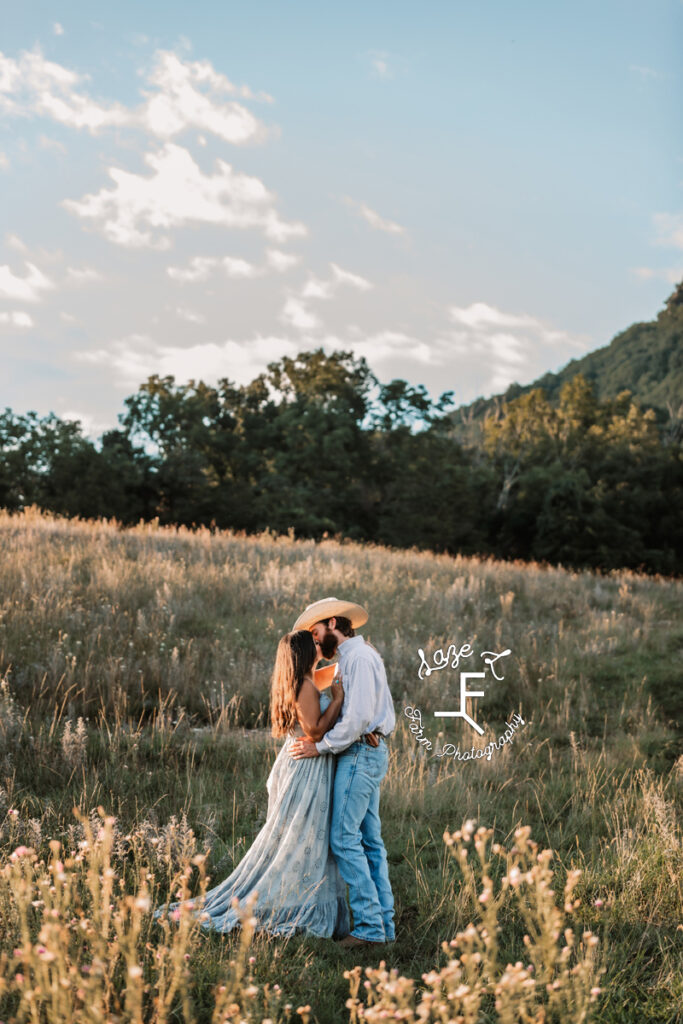 couple kissing in a field with a mountain in the background