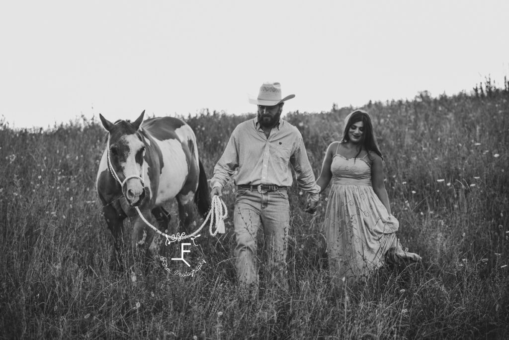 cowboy and fiancé with paint horse in black and white
