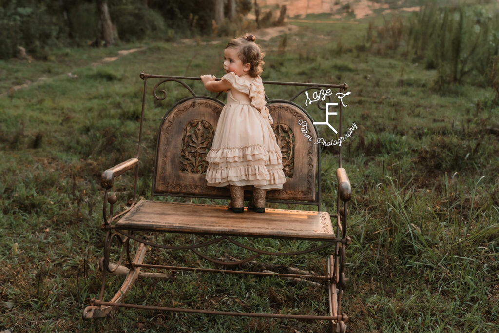 little girl in cowgirl boots standing backwards on rocker