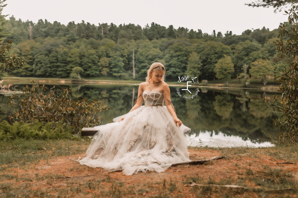 model sitting on bench in front of lake