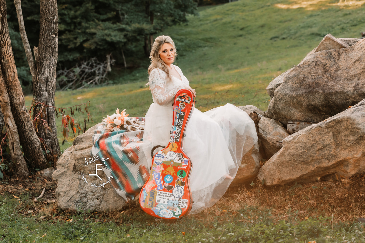 Bambi sitting with guitar case on rocks