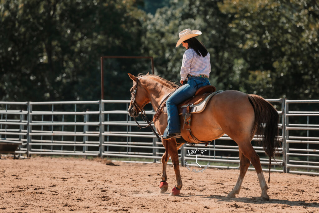 cowgirl riding horse away from camera
