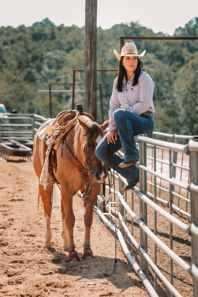 cowgirl sitting on fence with her horse