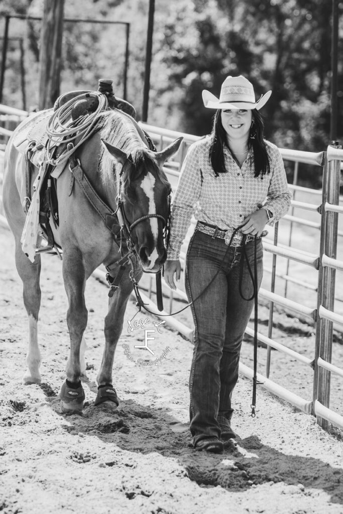 cowgirl walking with her horse in black and white