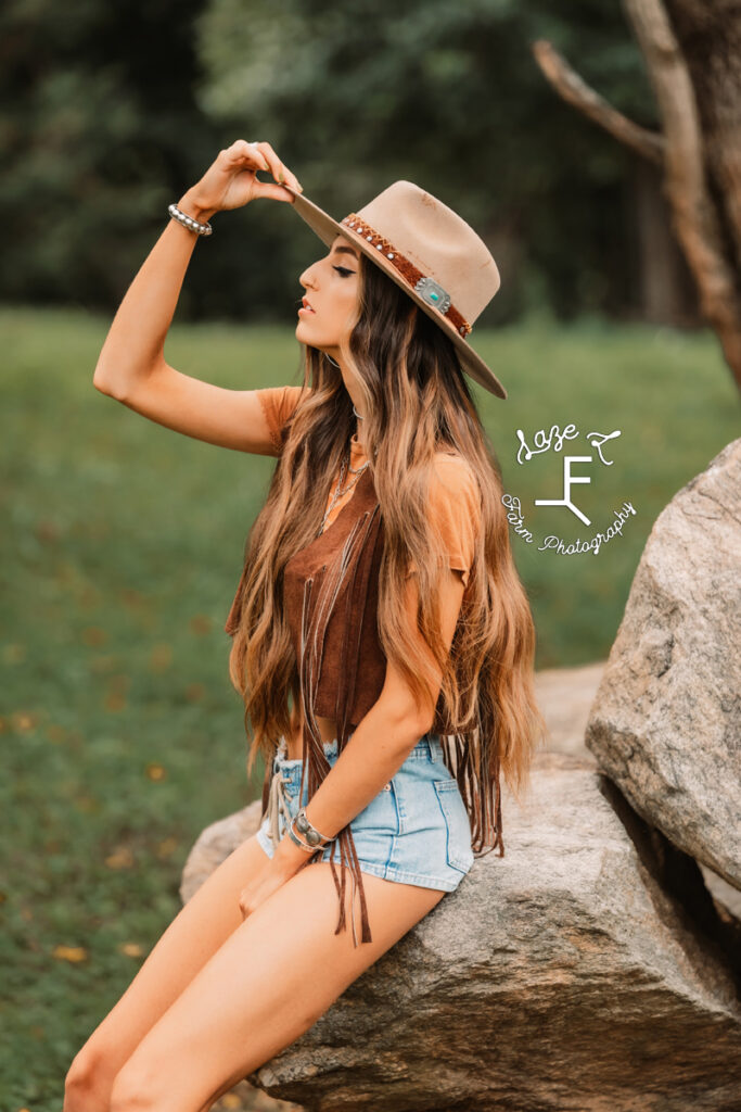 model with long brown hair tipping hat back