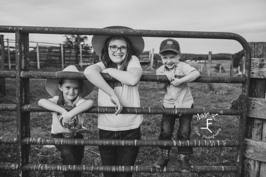 farm kids standing behind gate in black and white