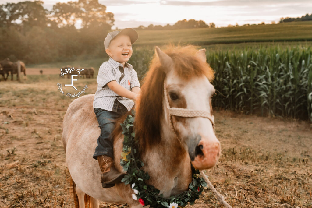 little boy riding pony smiling