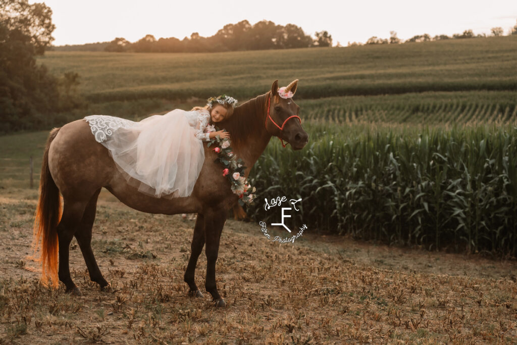 little girl sitting on unicorn dressed horse