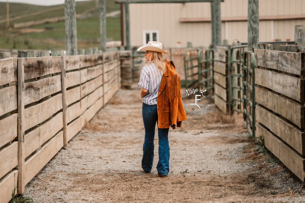 cowgirl walking away holding leather fringe jacket