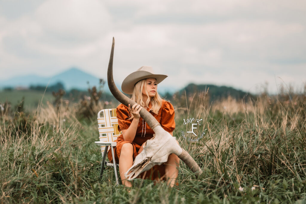 cowgirl sitting in vintage lawn chair holding long horn skull