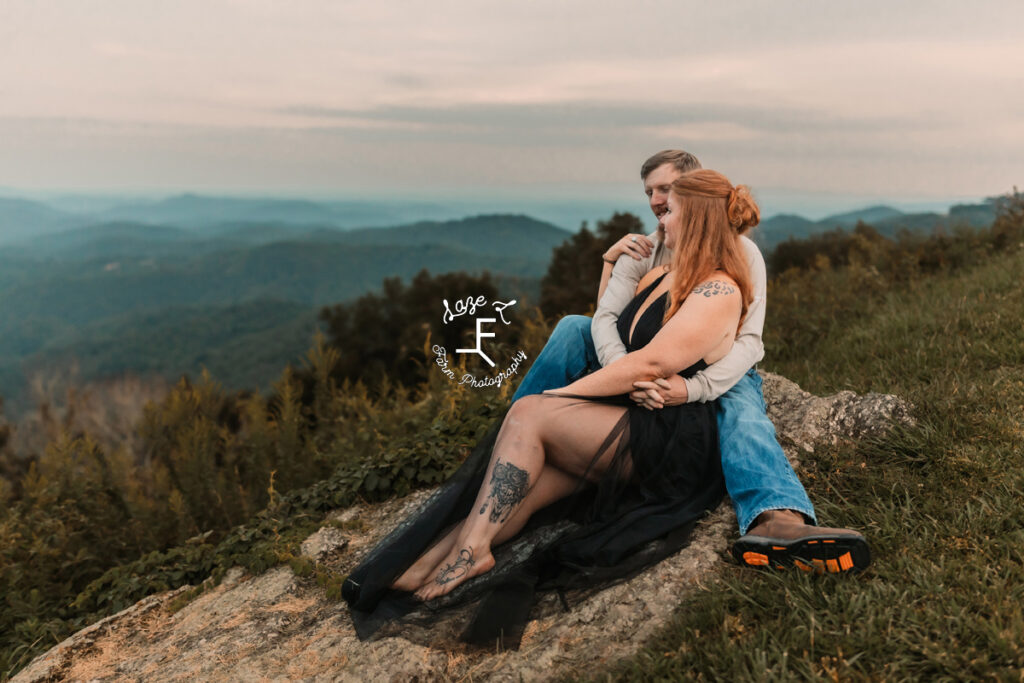 couple sitting on rock with mountains in the background