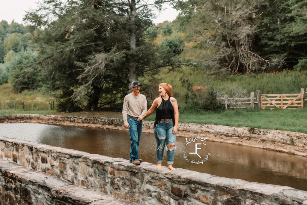 couple holding hands on rock wall