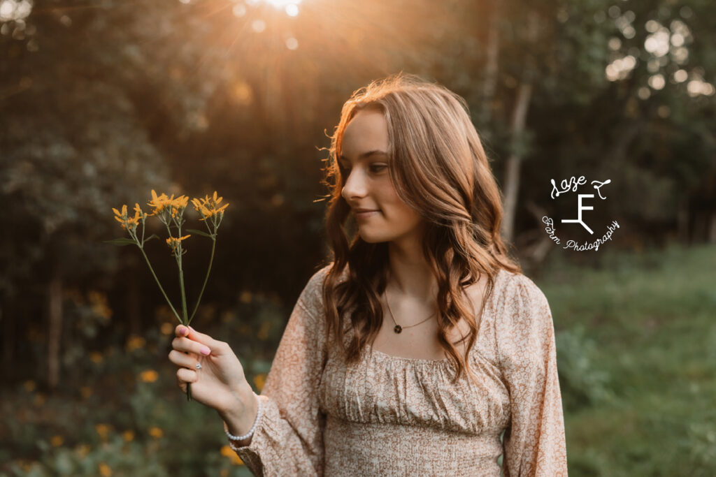 oldest daughter holding flowers with sun behind her