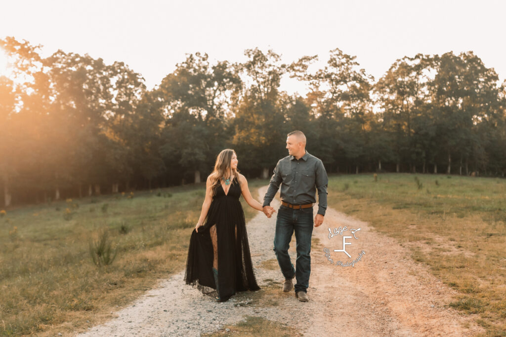 mom and dad walking down dirt road holding hands