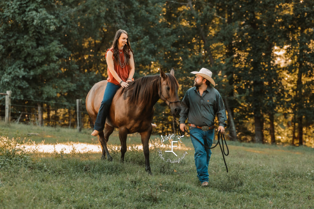 cowboy leading fiancé riding horse