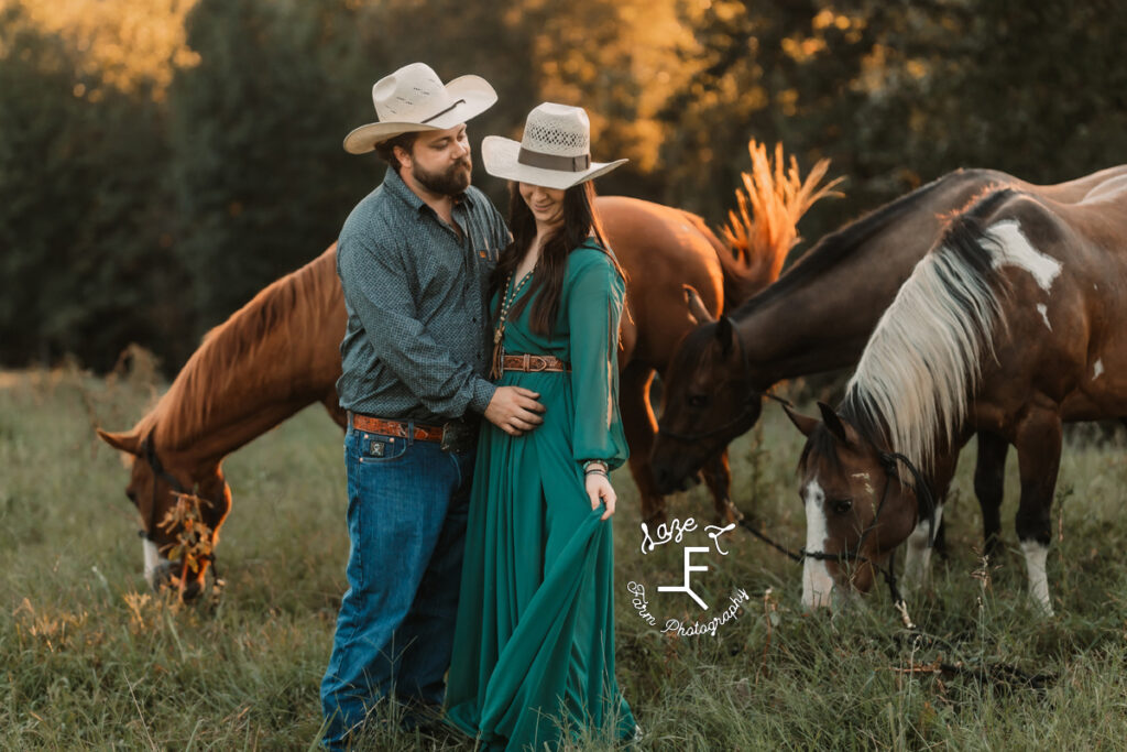 cowboy and cowgirl standing facing each other with 3 horses in the background