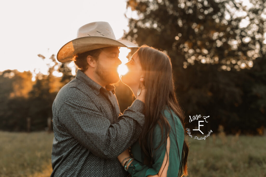 cowboy and fiance close together with sun in the background