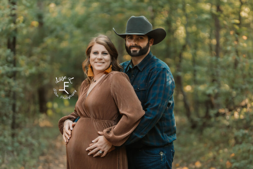 cowboy and pregnant wife smiling at camera