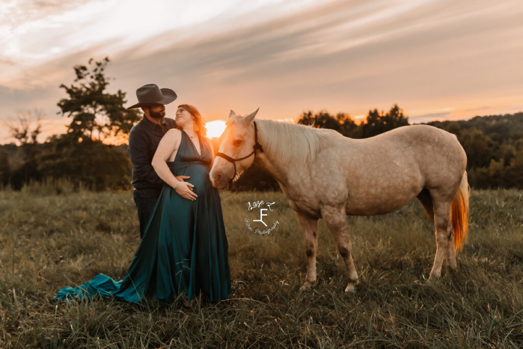 cowboy and pregnant wife with palomino horse at sunset