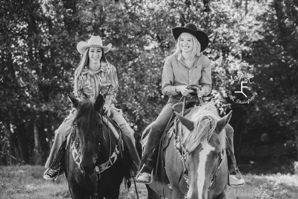 both cowgirls riding horses in black and white
