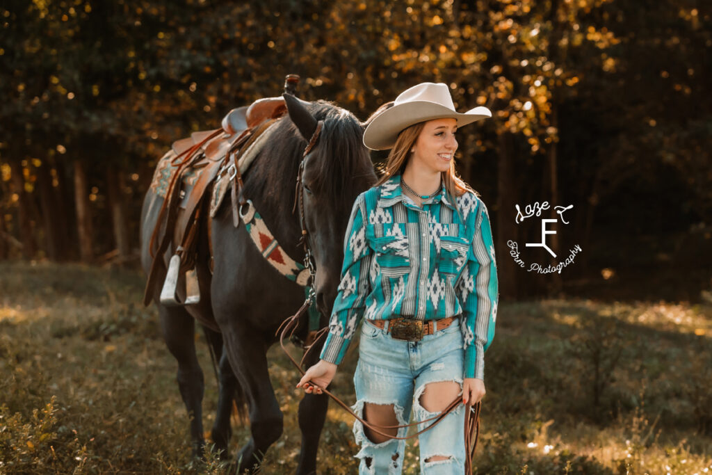 brunette cowgirl with black horse standing
